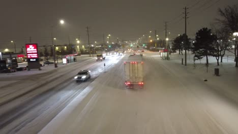 Aerial-tracking-follow-semi-truck-driving-through-snowy-road-at-night
