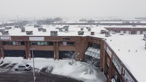 Snow-Falling-On-Establishments-With-Condensers-On-Rooftop-During-Winter-In-Mississauga,-Canada