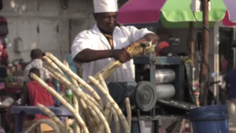 Man-folding-sugar-canes-to-press-and-make-juice-in-Unguja,-Zanzibar---Medium-close-up-shot