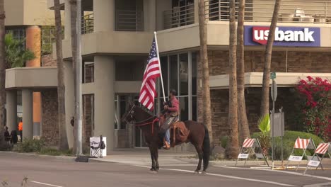 African-American-man-horse-riding-with-an-American-Flag-commemorating-Memorial-Day-in-Arizona,-USA---Wide-static-shot