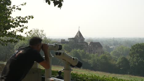 Enthüllungsaufnahme-Eines-Mannes,-Der-Den-Richmond-Park-Und-Das-Prächtige-Gebäude-Mit-Einem-öffentlichen-Fernglas-Bewundert