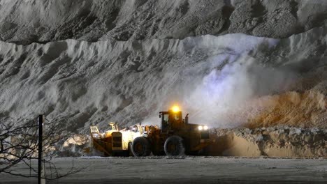 Snow-blower-attachment-clearing-up-the-snow-during-nighttime-at-a-slow-pace