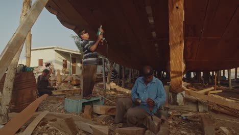 Artesanos-Utilizando-Taladro-Haciendo-Barco-Dhow-En-Sur,-Omán