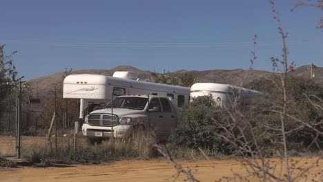 Trailer-park-with-motor-homes-and-a-pickup-truck-amidst-the-Arizona-Desert,-in-USA---Wide-static-shot