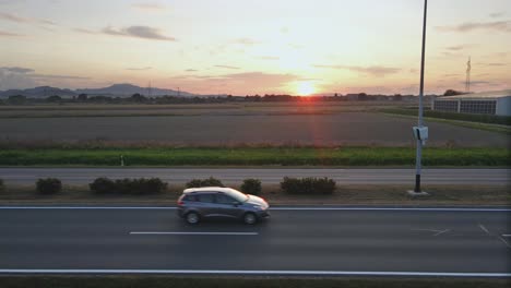 Radar-speed-control-camera-mounted-on-a-pool-on-the-highway-monitoring-busy-traffic-road-at-the-sunset-with-colorful-sky-and-natural-mountain-landscape