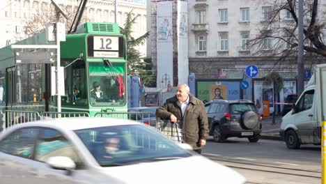 Old-green-tram-at-tramway-stop-in-city-center-of-Sofia-in-middle-of-car-traffic