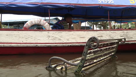 Submerged-Bench-In-River-Next-To-Taxi-Boat-With-Driver-Sitting-Down-In-Iquitos,-Peru