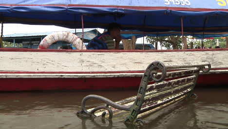 Banco-Sumergido-En-El-Río-Junto-Al-Barco-Taxi-Con-Conductor-Sentado-En-Iquitos,-Perú