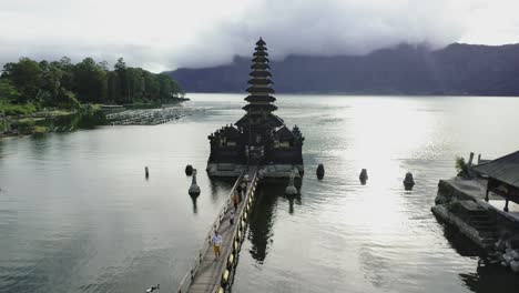 Balinese-family-wearing-traditional-clothing-walking-on-water-bridge-reaching-old-hindu-temple-for-a-blessing-ceremony