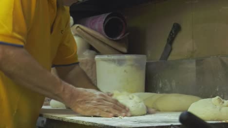 Baker-kneads-flour-dough-by-hand-folding-it,-in-Singapore-Food-Market---Medium-detail-shot
