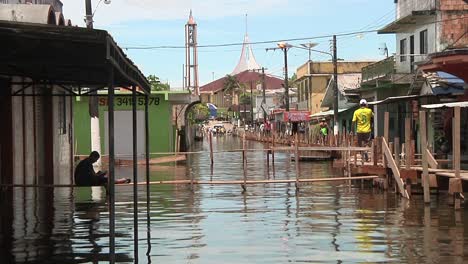 View-Of-Flooded-Street-With-People-Walking-On-Elevated-Walkways-In-Iquitos,-Peru