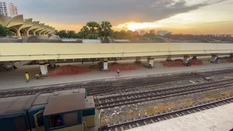 Estación-De-Tren-Desértica-De-Kamalapur-Con-Un-Vagón-Que-Llega-Lentamente,-Frente-A-Una-Puesta-De-Sol-Nublada,-Bangladesh