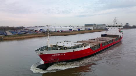 Finnish-containership-Marjatta-sailing-across-the-Oude-Mass-river,-Aerial-Tracking-shot