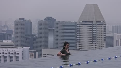 Beautiful-Girl-leaning-on-the-edge-of-Marina-Bay-Sands-infinity-pool-in-Singapore---Wide-Static-shot