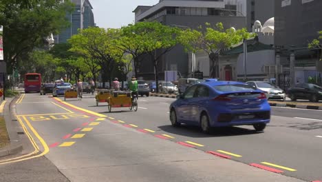 Rikschafahrer-Fahren-Auf-Der-Straße-In-Singapur-Vorbei-–-Kamerafahrt-Mit-Weitwinkelschwenk