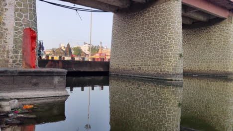 Spiegelung-Einer-Alten-Brücke-In-Einem-Godavari-Fluss-Mit-Weitem-Blick-Auf-Hinduistische-Tempel---4k