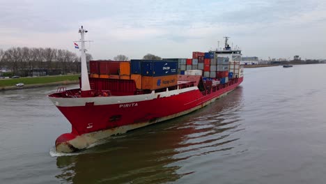Filmische-Parallaxe-Des-Mit-Frachtcontainern-Beladenen-Schiffes-Pirita,-Das-Durch-Den-Fluss-Oude-Mass-Fährt