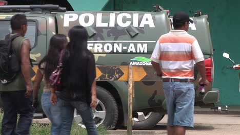 People-Walking-Past-Parked-Police-Trucks-Behind-Barrier-In-Peru