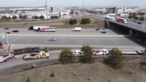 Aerial-drone-shot-of-a-accident-scene-with-an-overturned-truck-being-recovered-by-emergency-services-using-large-tow-truck-cranes,-Toronto,-Canada