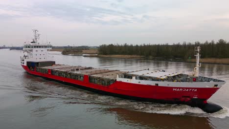 Finnish-containership-Marjatta-sailing-across-the-Oude-Mass-river,-Drone-shot