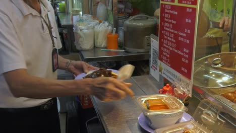 Man-being-served-plate-of-food-at-the-counter-in-Singapore-food-market---Medium-tilt-down-shot