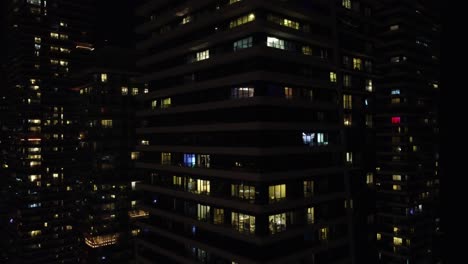 Paralaje-Aéreo-Alrededor-Del-Edificio-De-Oficinas-De-Apartamentos-Rascacielos-Durante-La-Noche
