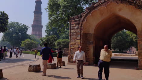 Tourist-Roaming-Around-The-Iconic-Monument-Qutub-Minar-Complex,-New-Delhi-,-India---4K-Tilt-Down