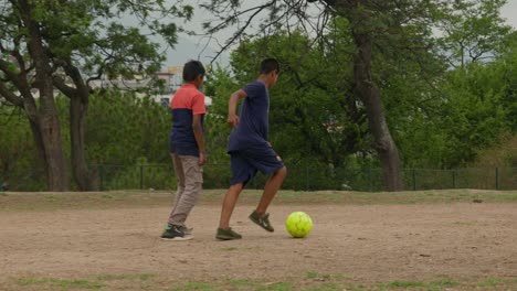Niños-Jugando-Al-Fútbol-En-Un-Campo-De-Tierra-Con-Una-Pelota-Amarilla,-En-Katmandú,-Nepal