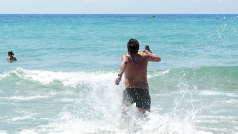 Man-on-Holiday-Running-Into-the-Blue-Ocean,-Slow-Motion,-Behind