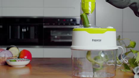 Hand-feeding-cucumber-into-food-processor,-making-fine-curly-slices