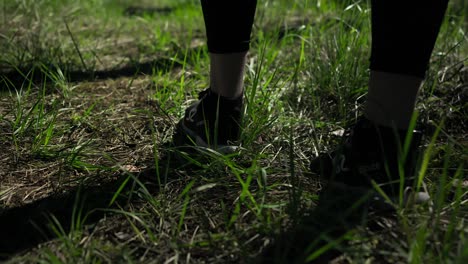 A-close-up-shot-captures-a-person-standing-in-snickers-on-the-grassy-ground,-ready-for-a-sunny-jog