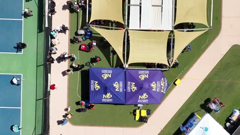 Aerial-view-rising-over-National-Pickleball-tournament-marquee-tent-and-blue-competition-court