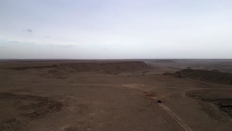 Coche-Que-Se-Acerca-Aéreo-Viajando-Por-Un-Camino-De-Tierra-En-El-Borde-Del-Mundo,-Riad