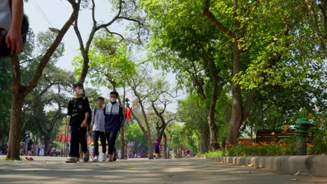Students-after-school-walking-back-home-on-the-road-with-Vietnamese-flags-flying-behind-them