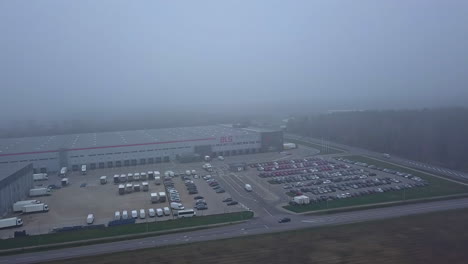 Aerial-view-of-warehouse-parking-lot-and-trucks,-foggy