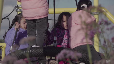 Young-girls-delightfully-play-on-a-swing-set-in-the-playground,-basking-in-the-warmth-and-joy-of-the-moment