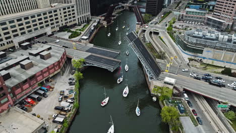 Aerial-view-of-sailing-boats-moving-through-a-raised-bridge,-in-downtown-Chicago,-USA