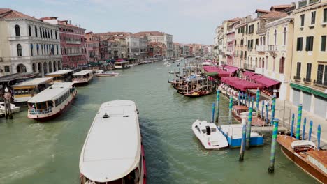 Venetian-tourist-tour-boat-passing-under-a-bridge-in-the-Grand-Canal-in-Venice,-Italy