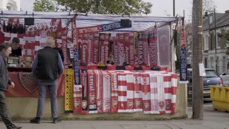 Soccer-fans-buying-soccer-merchandise-at-stalls-in-central-London,-that-sells-Arsenal-FC-scarfs,-jerseys-and-hats