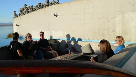 Friends-enjoying-warm,-sunny-evening-around-the-fire-on-big-terrace