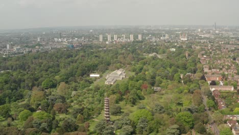 Toma-Aérea-En-Círculos-Rápidos-Sobre-Los-Jardines-De-Kew-Que-Revelan-El-Horizonte-Del-Centro-De-Londres