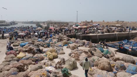 Establishing-shot-of-Essaouira-crowded-port-in-Marocco,-fishermen-passing-by