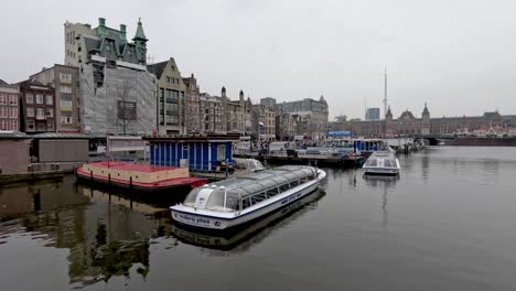 An-Einem-Bewölkten,-Bewölkten-Tag-Vertäuten-Kanalkreuzfahrtschiffe-Am-Damrak-In-Amsterdam