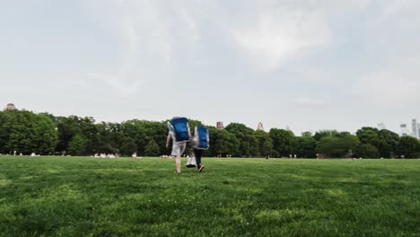 Timelapse-and-motionlapse-of-central-park,-Sheep-Meadow,-new-york,-open-space-of-green-grass-with-many-people-playing-sports-and-relaxing,-with-the-buildings-in-the-background