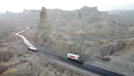 Aeril-drone-rotating-shot-over-trucks-passing-by-Buzi-Pass-top-along-Makran-Coastal-Highway-in-Balochistan,-Pakistan-on-a-sunny-day