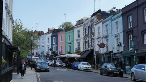 Colorful-Houses-of-Portobello-Road-in-Notting-Hill,-shops-and-people-walking
