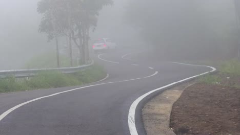 Weißes-Auto-Fährt-Bei-Nebel-Durch-Scharfe-Kurven-Auf-Der-Autobahn-In-Hügeln