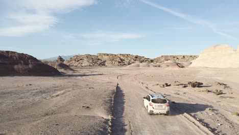 Folgen-Sie-Einem-Weißen-Subaru-Crosstrek-Durch-Den-Wüstenhügel-Der-Bentonithügel-In-Hanksville,-Utah,-An-Einem-Strahlend-Sonnigen-Tag-Und-Verrückten-Felsformationen