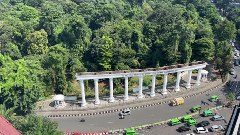 Botanical-garden-at-the-heart-of-city-Bogor,-showing-traffic-and-green-forest-of-Bogor-City-under-the-blue-sky