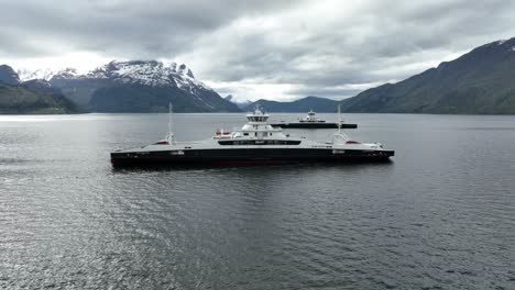 Los-Ferries-Eléctricos-Eidsfjord-Y-Gloppefjord-Se-Encuentran-En-Medio-De-Nordfjord-En-La-Conexión-Anda-lote---Vista-Aérea-Mostrando-El-Costado-De-Los-Barcos-Y-El-Fondo-Escénico---Noruega